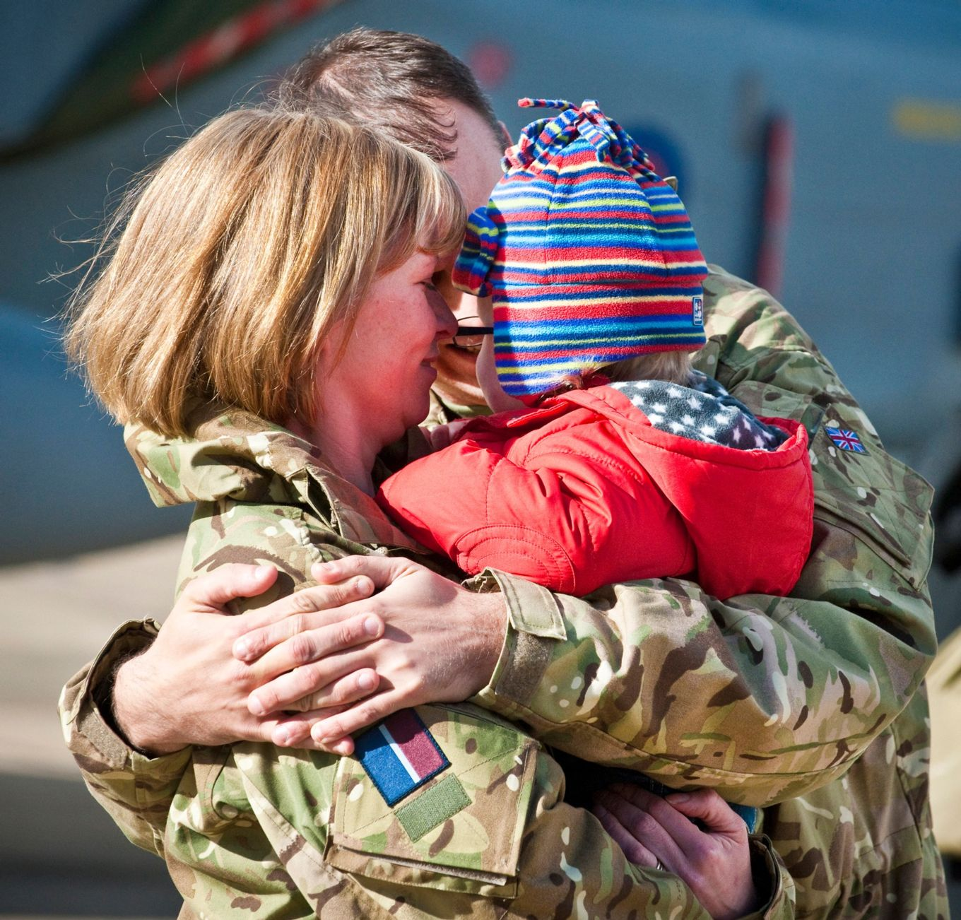 Image shows RAF aviator hugging with their child. 